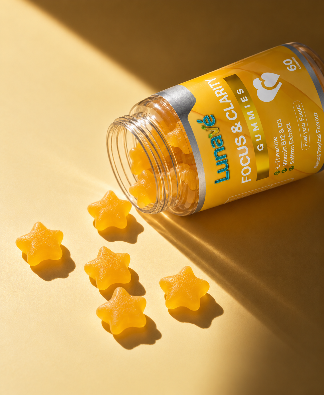 Lunavé Focus & Clarity gummies spilled from bottle on golden surface - star-shaped tropical flavour gummies with L-Theanine, Vitamin B12, D3 and Saffron Extract.