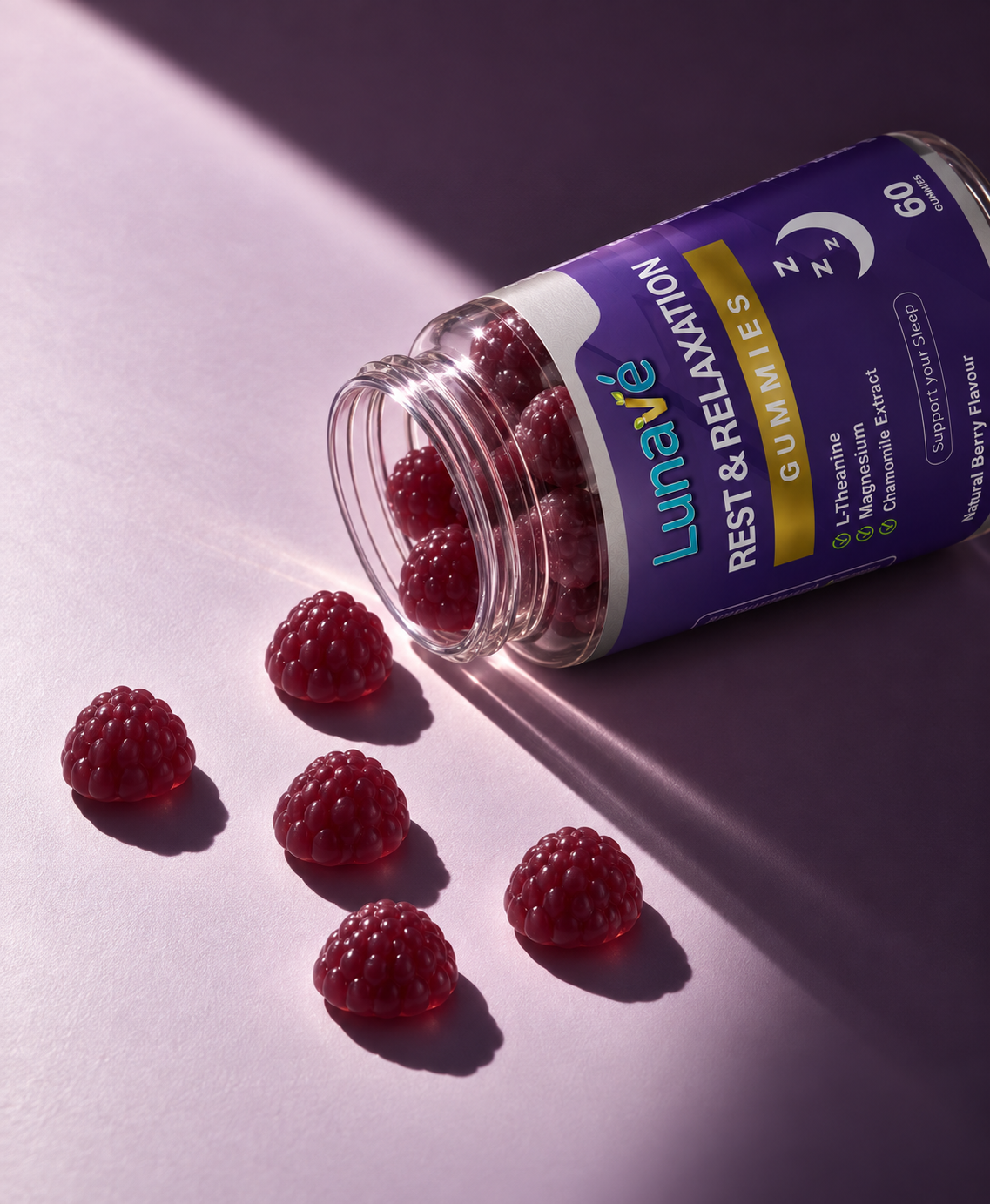 Lunavé Rest & Relaxation sleep gummies spilled from bottle on purple surface - raspberry-shaped berry flavour gummies with L-Theanine, Magnesium and Chamomile Extract.